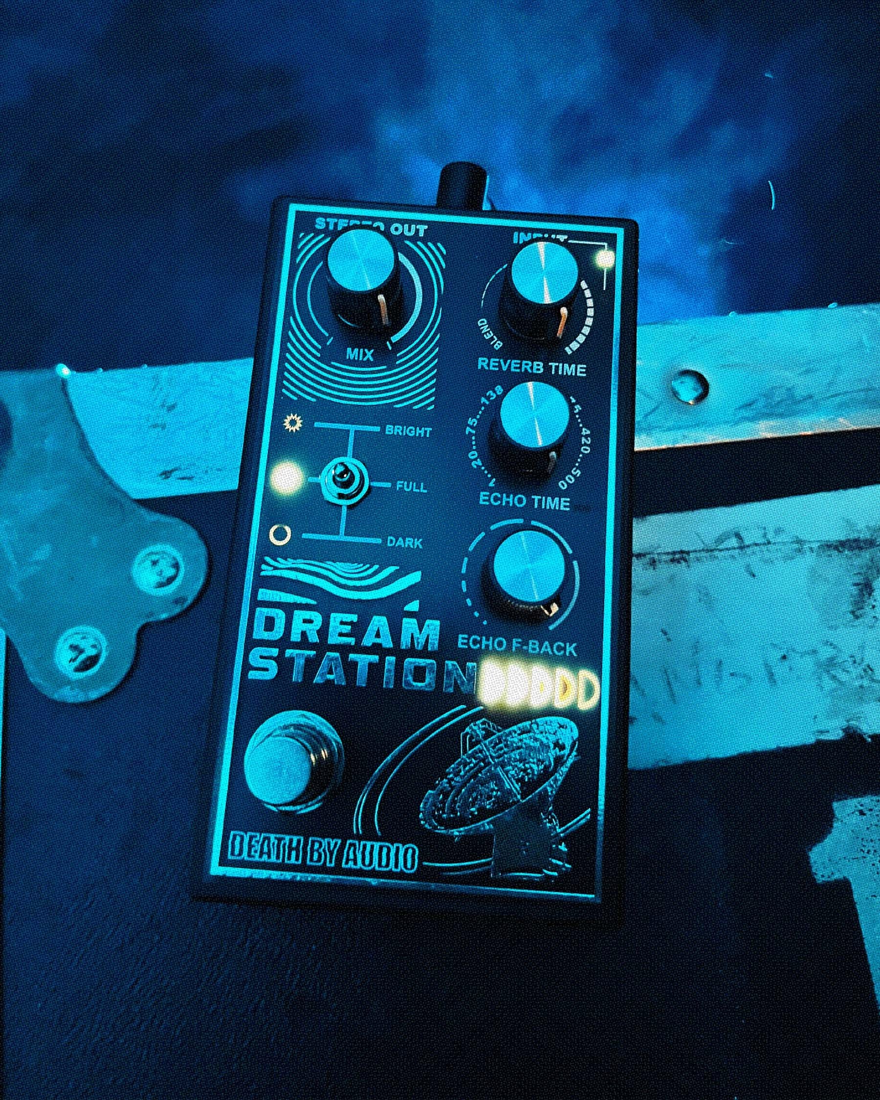 Death by Audio Dream Station pedal photographed on a weathered plank under blue stage lighting and haze