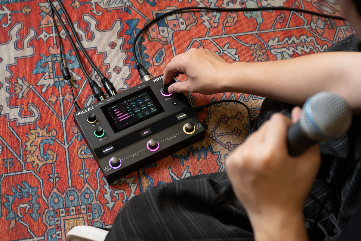 Hotone Voclas VE-300 on the floor, singer holding a microphone and turning a knob