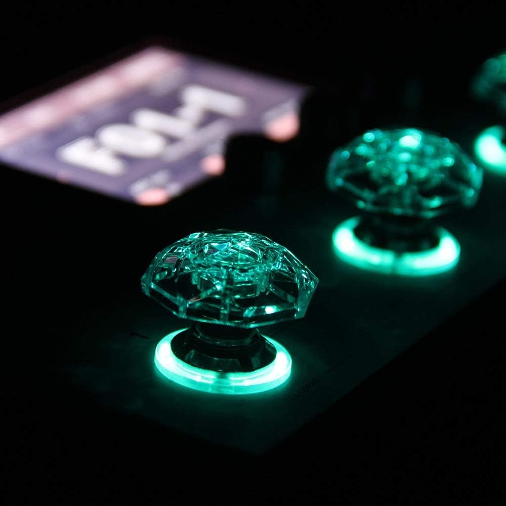 Close-up of two teal-glowing Hotone Karat Cap footswitch covers on a pedal top plate