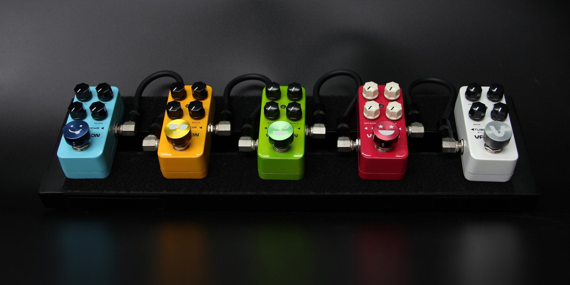 Valeton footswitch caps installed on a row of colored guitar pedals
