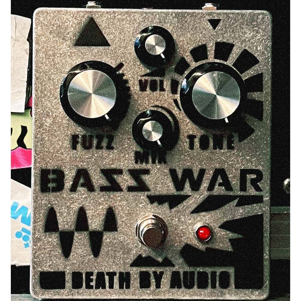 Death by Audio Bass War fuzz pedal photographed in use next to sticker covered gear