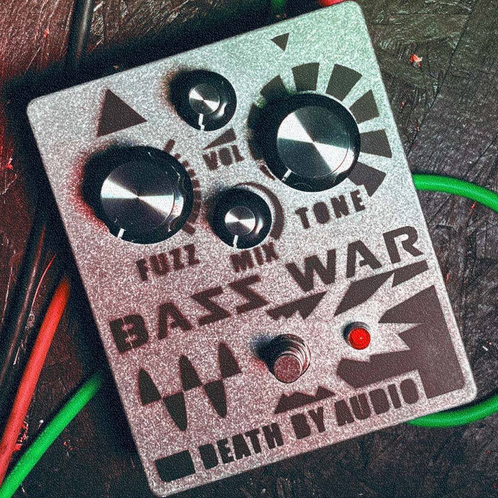 Death by Audio Bass War pedal on a dark floor with green and red patch cables running alongside it