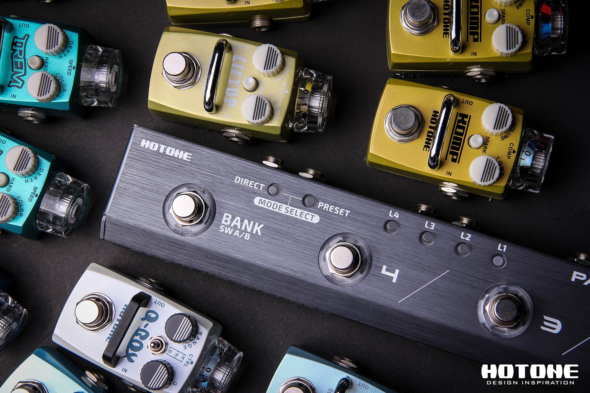 Overhead view of a colorful guitar pedalboard signal chain including a Hotone loop switcher
