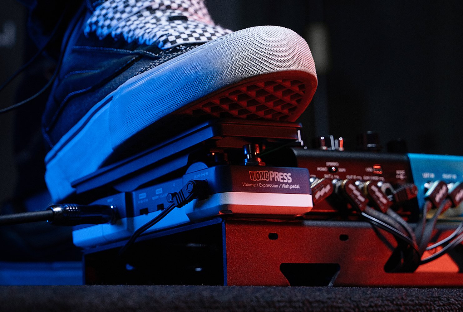 Sneaker on a pedalboard beside the Hotone SP-21 Wong Press pedal under stage lighting