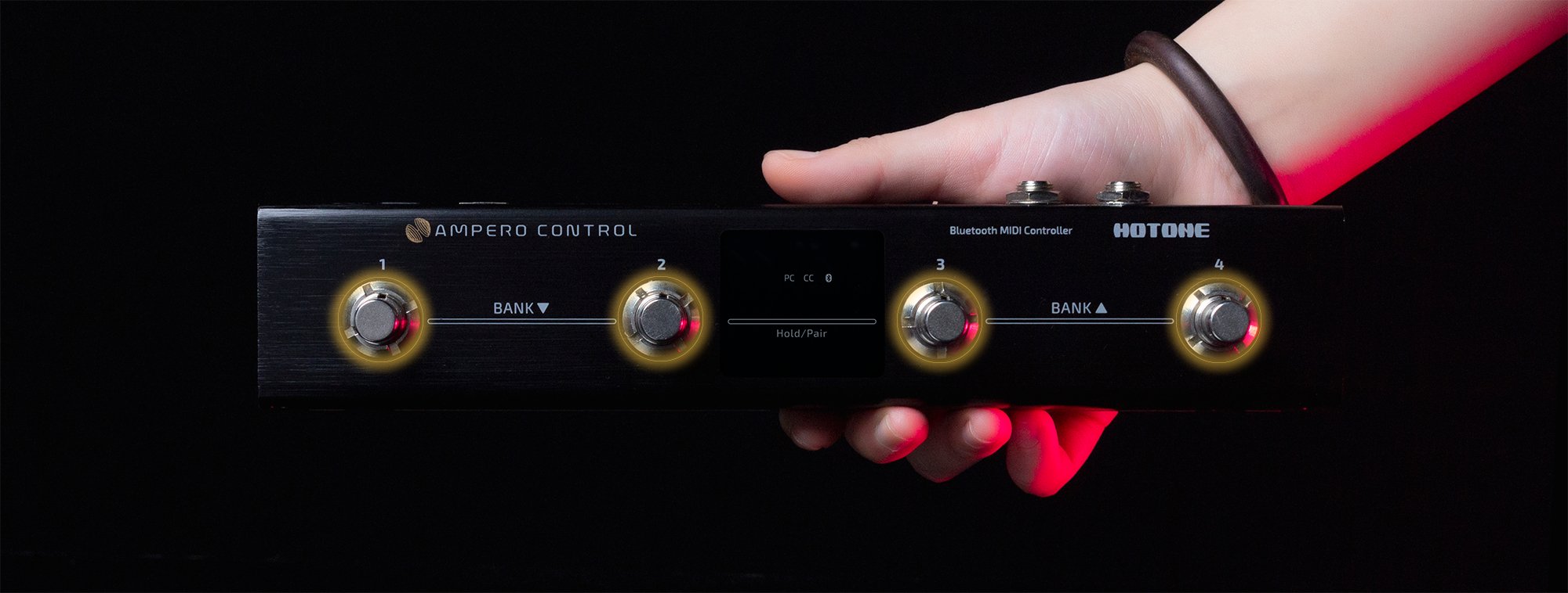 Hand adjusting a knob on the Hotone Ampero Control EC-4 foot controller in low light