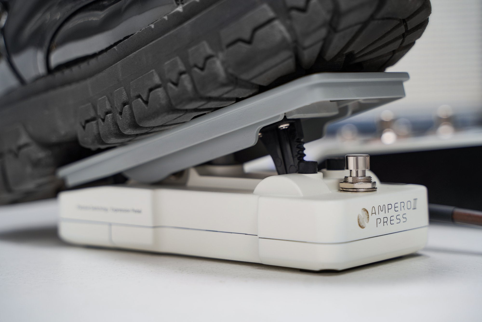 Sneaker-clad foot operating the Hotone Ampero II Press SP-35 pedal with connected cable