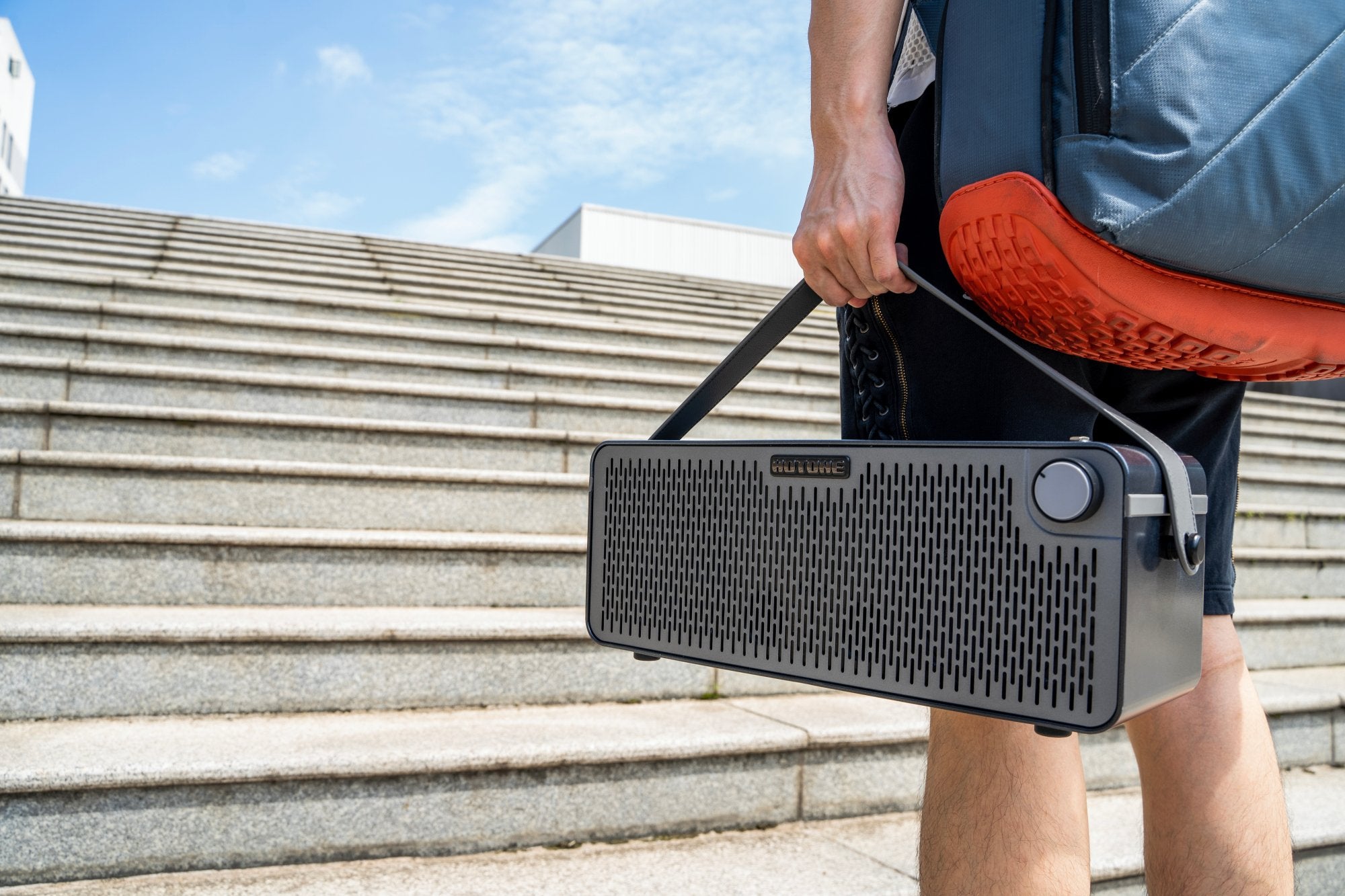 Person carrying the Hotone Pulze AP-30BK amplifier by its strap outdoors on steps