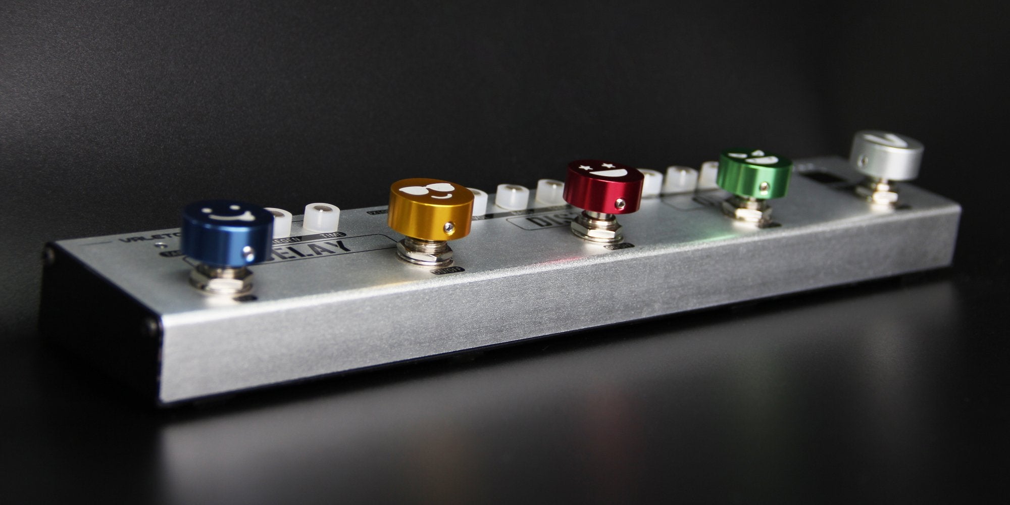 Five colored Valeton footswitch caps installed on a pedalboard mounting plate
