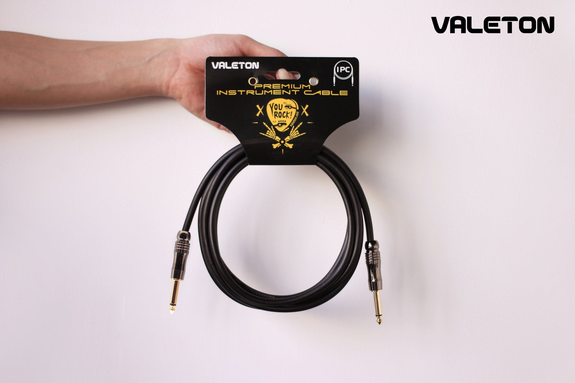 Hand holding the Valeton VGC-3 cable on its retail packaging