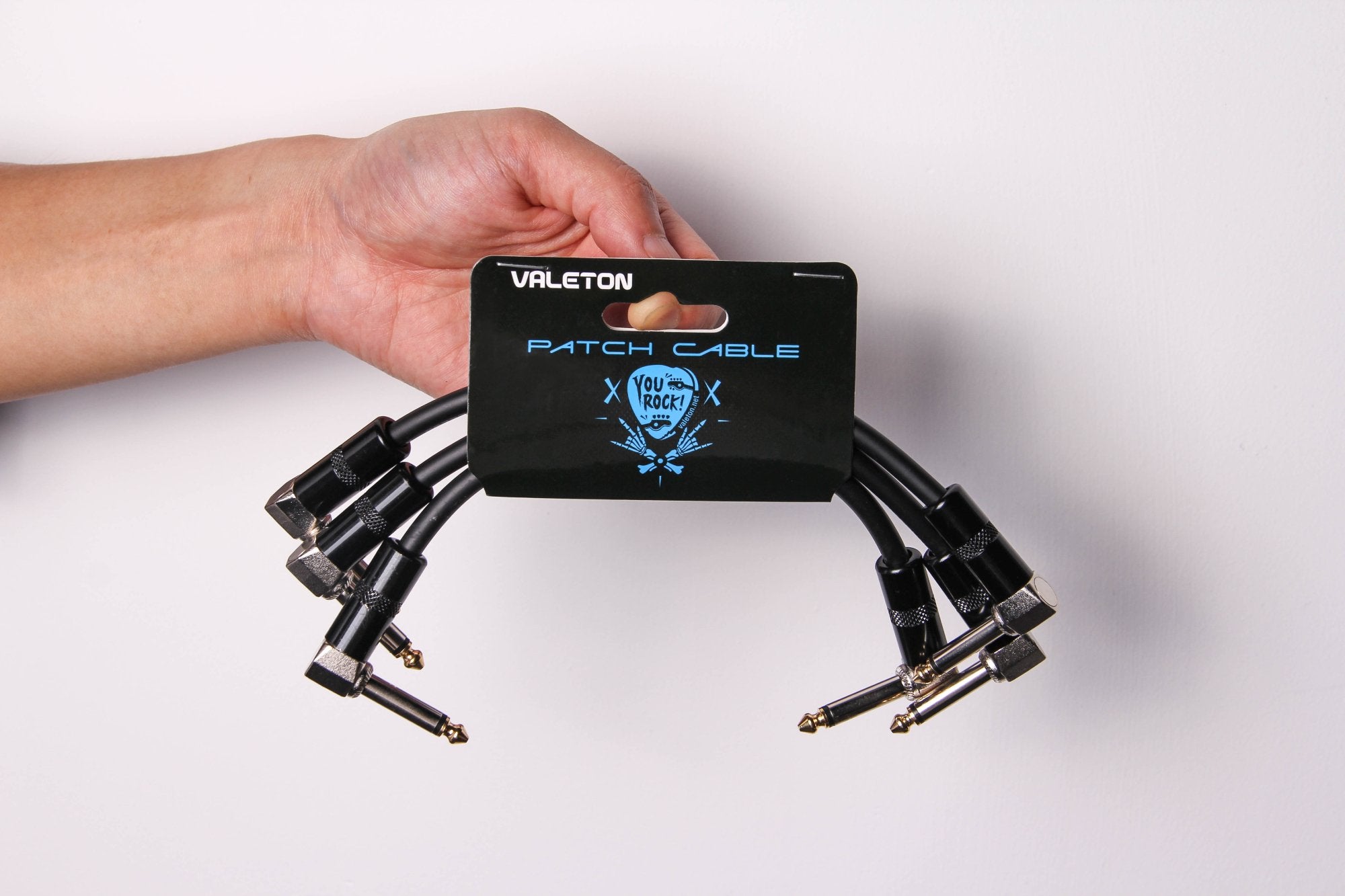 Hand holding the Valeton VPC-3 patch cable 3-pack on its retail packaging