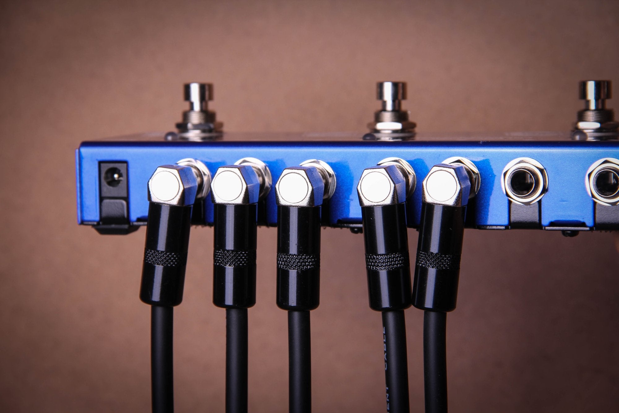 Multiple Valeton VPC-3 patch cables wiring a row of pedals on a blue pedalboard